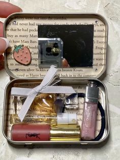 an open tin box with various items in it, including lipstick and other things inside