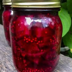 two jars filled with red liquid sitting on top of a wooden table