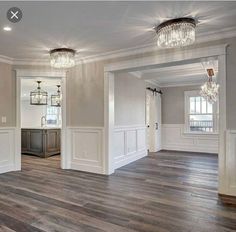 an empty living room with wood floors and chandeliers