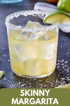 a close up of a drink in a glass with ice and limes around it