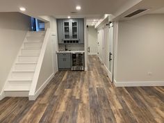 an empty living room with stairs leading up to the kitchen