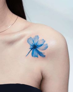 a woman's shoulder with a blue flower tattoo on the left side of her chest