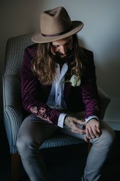 a man sitting in a chair with a hat on his head and tattoos on his arm