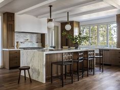 a large kitchen with wooden floors and white walls, along with marble counter tops on the island