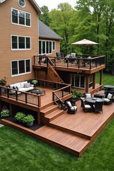 a deck with patio furniture and an umbrella on it in front of a large house