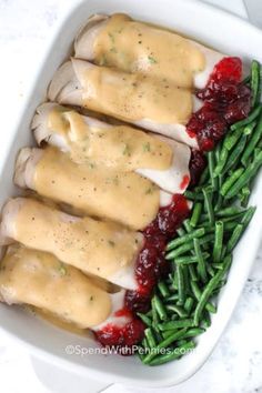 a white casserole dish with green beans and cranberry sauce on top