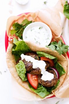 a pita filled with meat, lettuce and tomatoes on top of it