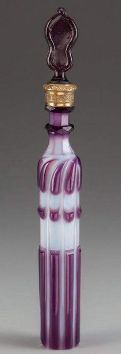 a purple and white glass bottle with a gold top