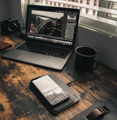 an open laptop computer sitting on top of a wooden desk next to a cup of coffee