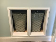 two white baskets sitting in the corner of a room next to each other on top of a shelf