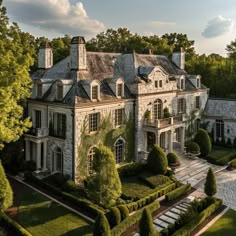 an aerial view of a large house with hedges and trees in the foreground, surrounded by greenery