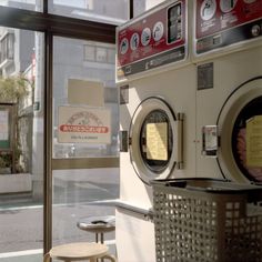 a washer and dryer sitting in front of a window next to a table