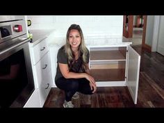 a woman kneeling down in front of an oven