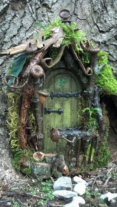 an image of a fairy house made out of tree branches and mossy plants on the ground