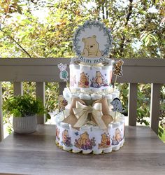 a three tiered winnie the pooh diaper cake on a wooden table outside