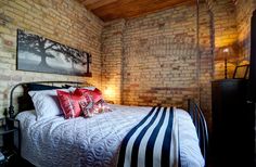 a bedroom with brick walls and a bed that has red pillows on top of it