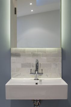 a bathroom sink under a large mirror in front of a wall mounted faucet