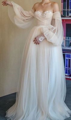 a woman in a white dress standing next to a book shelf