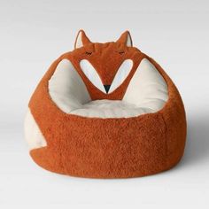 an orange and white fox dog bed on a gray background with the head of a cat