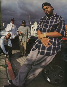 a group of young men standing next to each other on a city street with clouds in the background