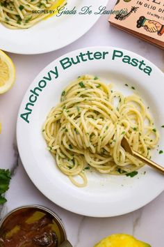 there is a plate of pasta on the table with lemons and parsley next to it