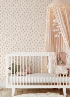 a white crib in front of a pink wallpaper