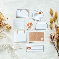 several pieces of paper with stickers on them next to some dried flowers and leaves