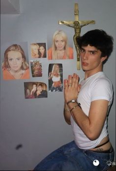 a young man sitting in front of a cross with pictures on the wall behind him