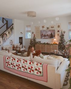 a woman sitting on a couch in a living room with christmas decorations and garlands