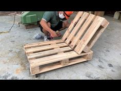 a man working on a wooden bed frame in the process of being made from pallets