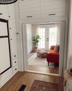 a living room filled with furniture and a large door leading to another room that has white walls