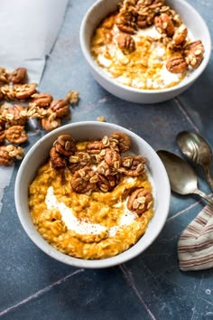 two bowls filled with oatmeal and pecans on top of a table