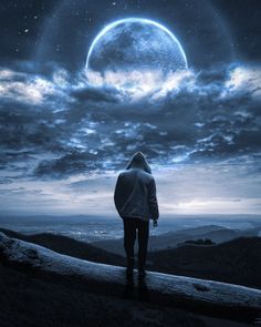 a man standing on top of a hill under a full moon