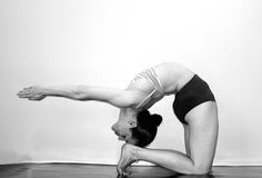 a woman in black and white doing yoga on the floor with her hands behind her head