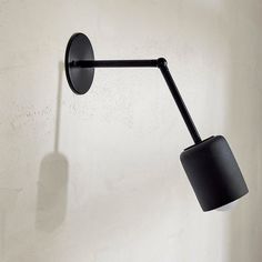 a black wall mounted light on the side of a white wall