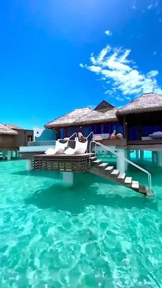 the water is crystal blue and clear with some huts on it's roof over looking the ocean