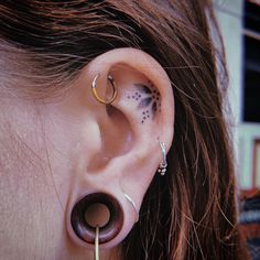 a woman with black dots on her left ear has an ear piercing in the shape of a circle