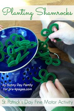 a child is playing with green plastic letters on a blue bowl and holding it in their hands