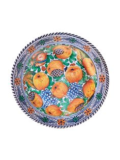 a decorative plate with oranges and grapes painted on the front, sitting on a white surface