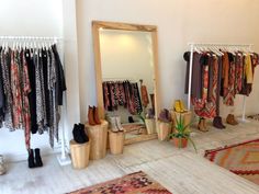 a room filled with lots of different types of clothing hanging on clothes racks and mirrors