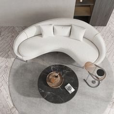 a white couch sitting on top of a gray rug next to a table and chair