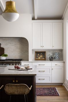 a kitchen with white cabinets and an island in front of a window that has a painting on it