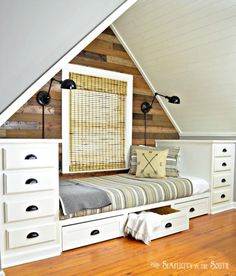 an attic bedroom with white drawers and storage underneath the bed is decorated in wood planks