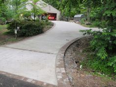 a driveway with a fire hydrant in the middle and trees around it on either side