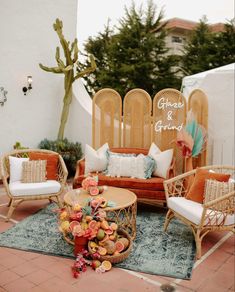 an outdoor seating area with wicker furniture and flowers on the rug in front of it