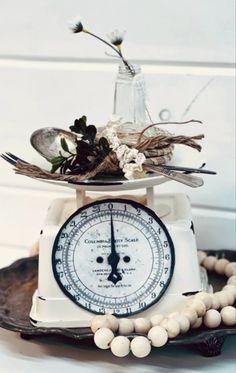 an old fashioned kitchen scale with flowers and spoons on it sitting on a plate