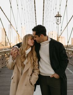 a man and woman standing on a bridge with their arms around each other as they kiss