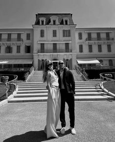 a man and woman standing in front of a large building with steps leading up to it