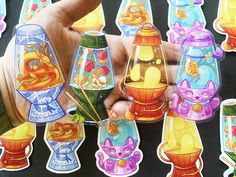 a hand is holding some colorful stickers in front of many different colored vases