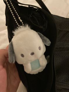 a small stuffed animal hanging from a black bag with a chain around it's neck